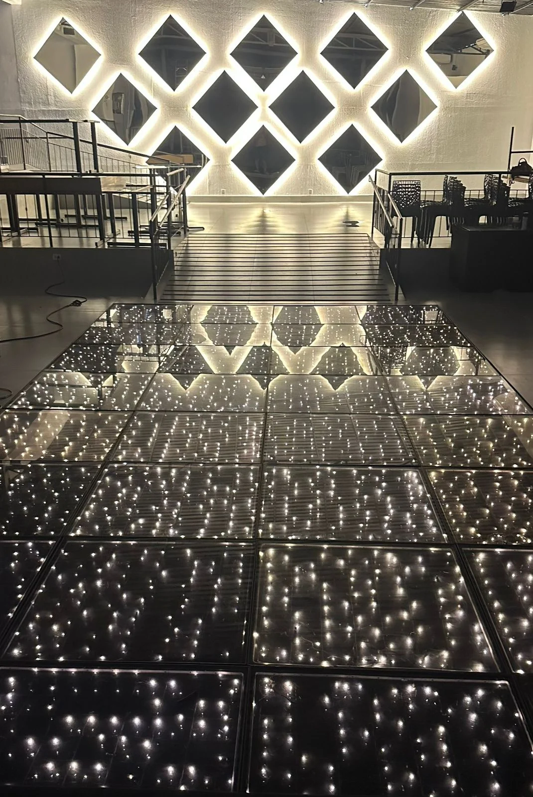 Parede de espelhos losangos e iluminação cênica