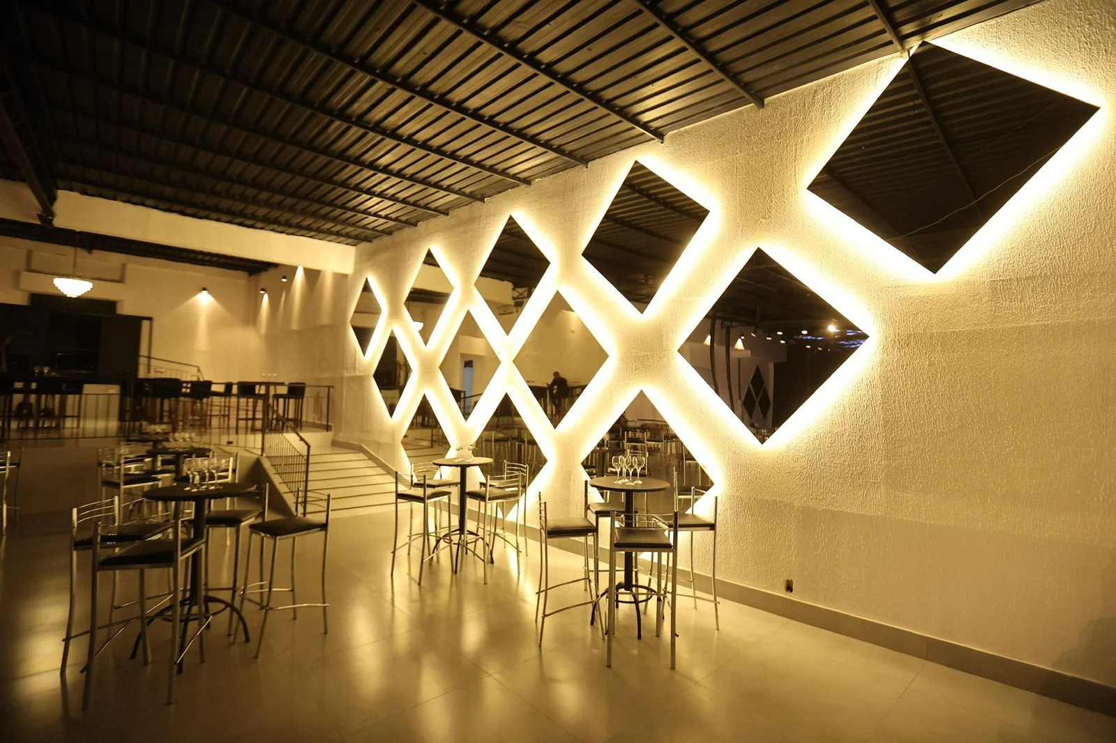 Lounge decorado com mesas e parede espelhada